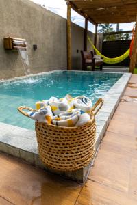 a basket of towels sitting next to a swimming pool at Nareia Casa Milagres in São Miguel dos Milagres