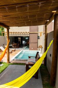 a yellow hammock on a patio with a pool at Nareia Casa Milagres in São Miguel dos Milagres