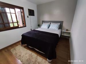 EncantadoPousada com vista para o Cristo 2的一间卧室配有一张带黑色毯子的床和窗户。