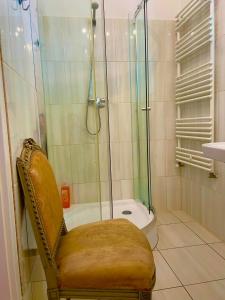 uma casa de banho com um chuveiro com uma cadeira e uma banheira em Villa Luca em Mosonmagyaróvár