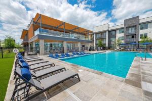 a swimming pool with lounge chairs in front of a building at Elegant & Luxurious Modern Apartment with Southern Charm in Fort Worth