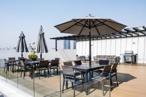 een terras met tafels, stoelen en een parasol bij New apartments in building with pool, rooftop and gym in Condesa in Mexico-Stad