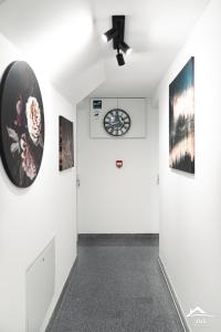 un corridoio con pareti bianche e un orologio sul muro di J&S Apartments a Niš