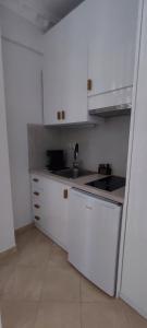 una pequeña cocina con armarios blancos y fregadero en atoll 'Paris-Alexandre', en Gythio