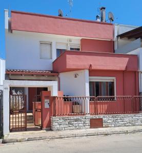 una casa rossa e bianca con cancello e recinzione di Villa Iris a Galatone