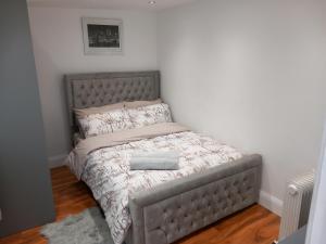 uma cama com uma cabeceira cinzenta num quarto em Heronsgate GH013 em Erith