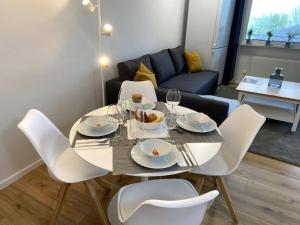 a table with white chairs and plates and wine glasses at 1-Zimmerapartment mit Burgblick in Bad Liebenzell