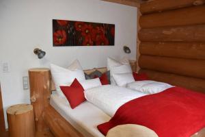 a bedroom with a bed with red and white pillows at Chalet Enzian Bayerwald in Arnbruck