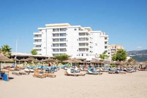 een strand met stoelen en parasols en een groot gebouw bij TreA Accomodations - On Private Beach with sunbed & umbrella in Vlorë