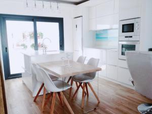 eine weiße Küche mit einem Holztisch und Stühlen in der Unterkunft Apartamento MarySol B con Terraza y Piscina privada in Benalmádena