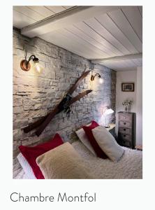 - une chambre dotée d'un mur en pierre et d'un lit avec des oreillers rouges dans l'établissement La Table d'Elodie, à Le Béage