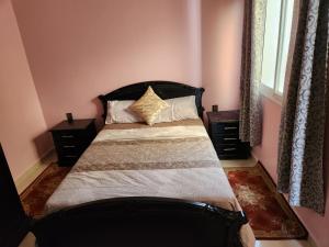 een slaapkamer met een bed met 2 nachtkastjes en een raam bij Tanger méditerranée in Tanger