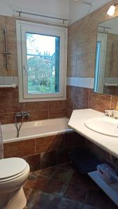 bagno con lavandino, servizi igienici e finestra di Mouse House a Gouviá