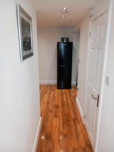 a hallway with a black refrigerator in a room at Heronsgate GH013 in Erith