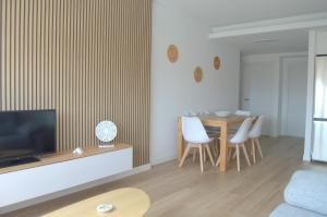 sala de estar con TV, mesa y sillas en Apartamentos Son do Faro Fisterra, en Finisterre
