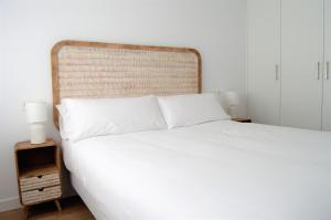 フィニステレにあるApartamentos Son do Faro Fisterraの白いベッド1台(木製ヘッドボード付)が備わるベッドルーム1室が備わります。