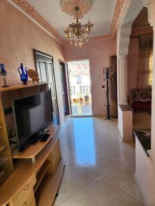 een grote woonkamer met een televisie en een kroonluchter bij Tanger méditerranée in Tanger