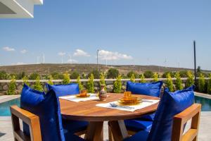 een houten tafel en blauwe stoelen op een patio bij Amazing Villa with Private Pool in Alacati Cesme in Alacati