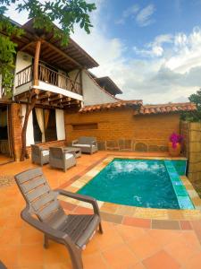 a swimming pool with a chair and a house at Cabañas el Nopal in San Gil