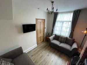 een woonkamer met 2 banken en een televisie bij The Railway Cottage Bridgnorth in Bridgnorth