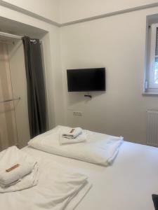 a bedroom with two white beds with a tv on the wall at Suite 2 in Neustadt an der Waldnaab
