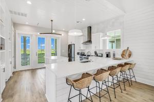 a white kitchen with a large island with bar stools at Sunshine Daydream in Port Aransas