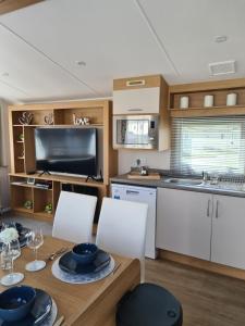 a kitchen and dining room with a table and chairs at Private Caravan Camber Sands in Camber