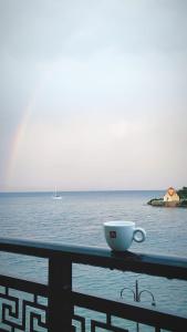 a cup of coffee sitting on a railing overlooking the ocean at l' atoll d' Helene in Gythio