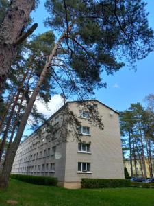 duży budynek z drzewami przed nim w obiekcie Zvejnieku apartamenti w mieście Roja