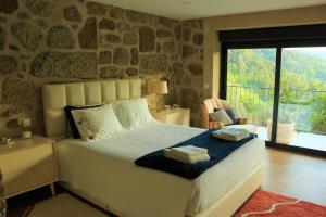 ein Schlafzimmer mit einem Bett mit einer Steinmauer in der Unterkunft Vila de Campos - Gerês in Vieira do Minho