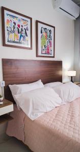 uma cama num quarto com duas fotografias na parede em Sofisticado, NOVO e Moderno! em Petrolina