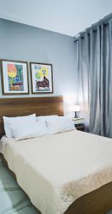 um quarto com uma grande cama branca com duas fotografias na parede em Sofisticado, NOVO e Moderno! em Petrolina