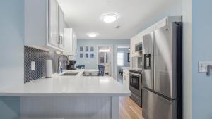 a kitchen with white cabinets and a stainless steel refrigerator at Red Neptune by Nautical Properties in Panama City Beach