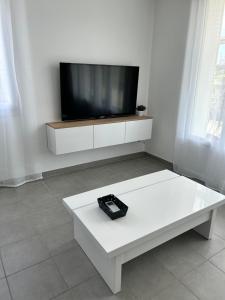 una mesa de centro blanca con TV en una pared blanca en L'Entre Deux Rêves, en Beaumont-lès-Valence