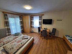 a room with two beds and a desk and a television at Kirchenwirt in Kaumberg