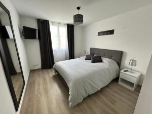 1 dormitorio con 1 cama blanca grande y espejo en L'Entre Deux Rêves, en Beaumont-lès-Valence