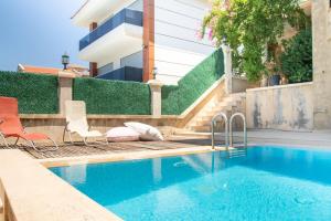 a swimming pool with chairs next to a building at Enchanting Villa with Backyard in Cesme near Beach in Alacati