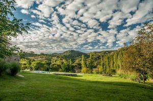 a park with a grassy field and a sky with clouds at Cabaña Molle by Lugar in El Manzano