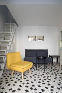 sala de estar con silla amarilla y sofá en Xenia Apartments - Moderno appartamento in Fondazione Prada, en Milán