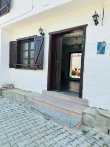 uma porta da frente de um edifício branco com uma janela em village house kazdağları otel & restaurant em Edremit