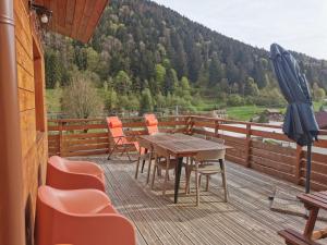 a wooden deck with a table and chairs and an umbrella at Chalet individuel - Panoramique montagnes & Proche Lacs in La Bresse
