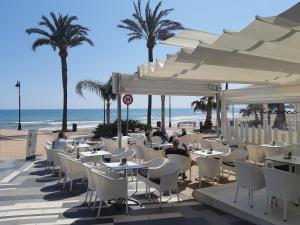 un ristorante sulla spiaggia con persone sedute ai tavoli di Traum-Ferienwohnung direkt am Meer ad Alcossebre