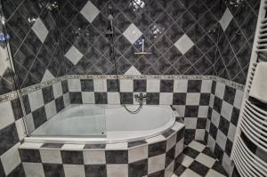 a bathroom with a black and white tiled tub at Kossuth Vendégház in Tolna