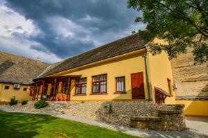 a yellow house with a stone wall at Kossuth Vendégház in Tolna