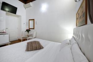 ein weißes Bett in einem weißen Zimmer mit einem Tisch in der Unterkunft Roman Nights in Rom