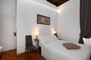 ein Schlafzimmer mit einem weißen Bett und einem Stuhl in der Unterkunft Roman Nights in Rom
