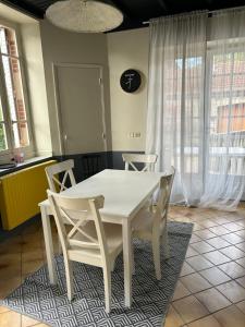 una mesa blanca y sillas en una habitación con ventanas en Maison mitoyenne dans quartier calme, en Saleich