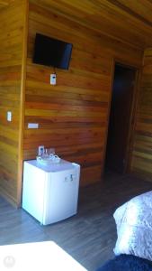 een kamer met een tv aan een muur met een tafel bij POUSADA RECANTO DOS VAGA-LUMES in Urubici