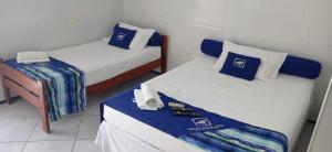 two beds in a small room with blue and white at Hotel Arco-Íris in Itapipoca