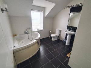 a bathroom with a tub and a toilet and a sink at Vista Mara in Donegal